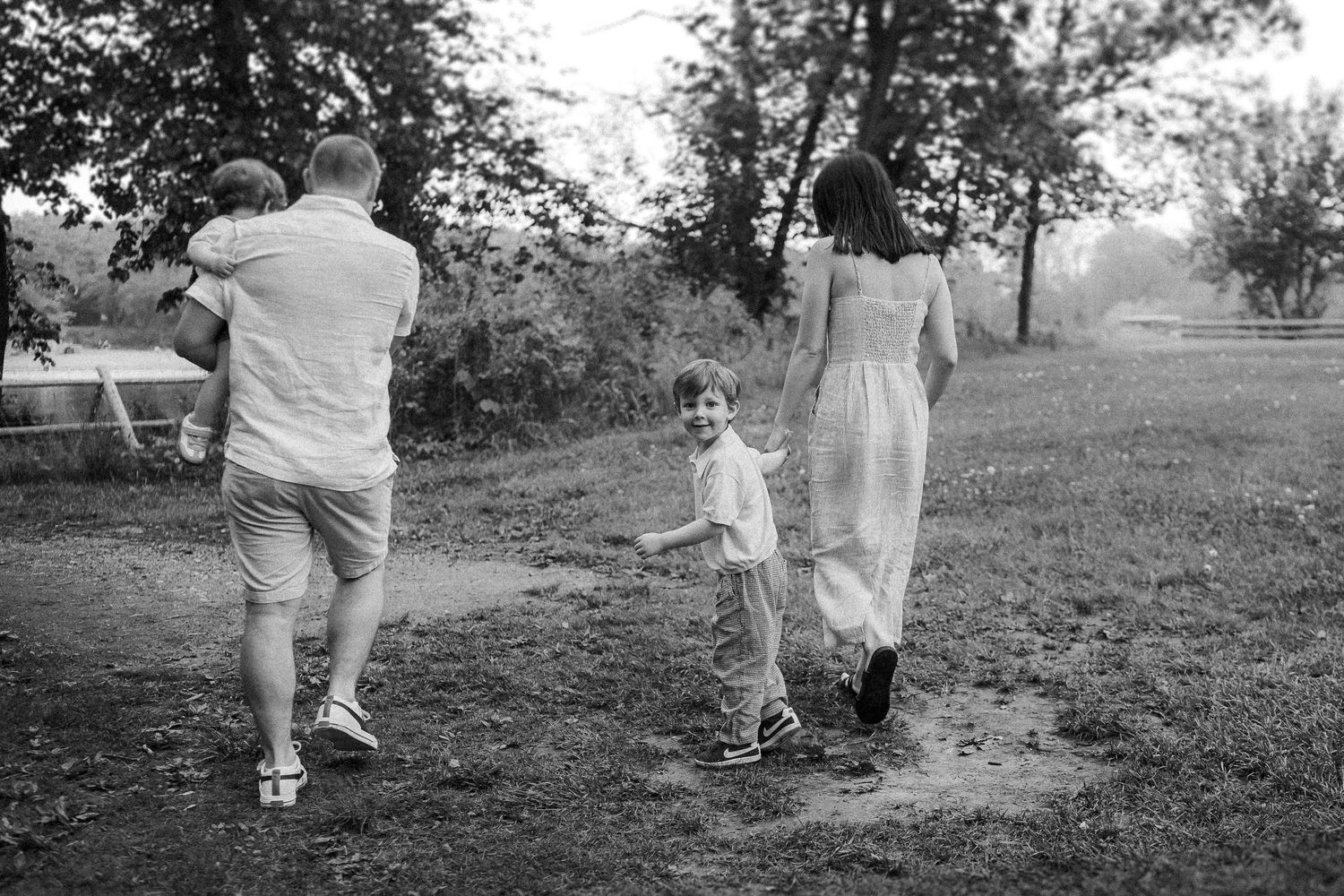 A family walks together through a park on a sunny afternoon in black and white.