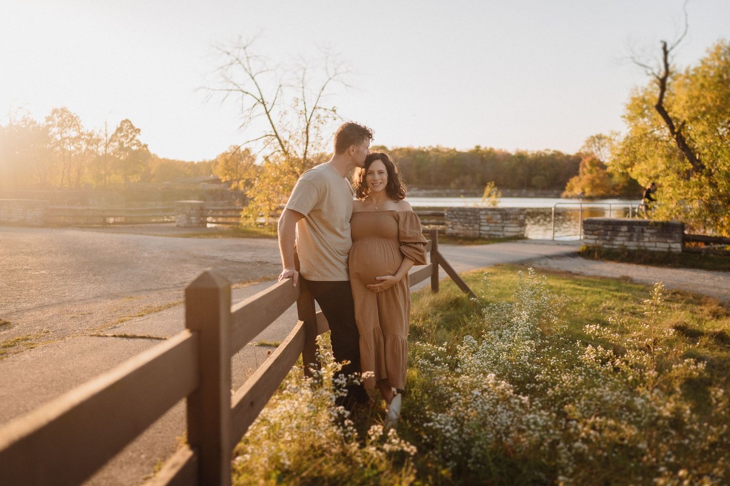 Couple shares intimate moment by rustic fence during sunset.
