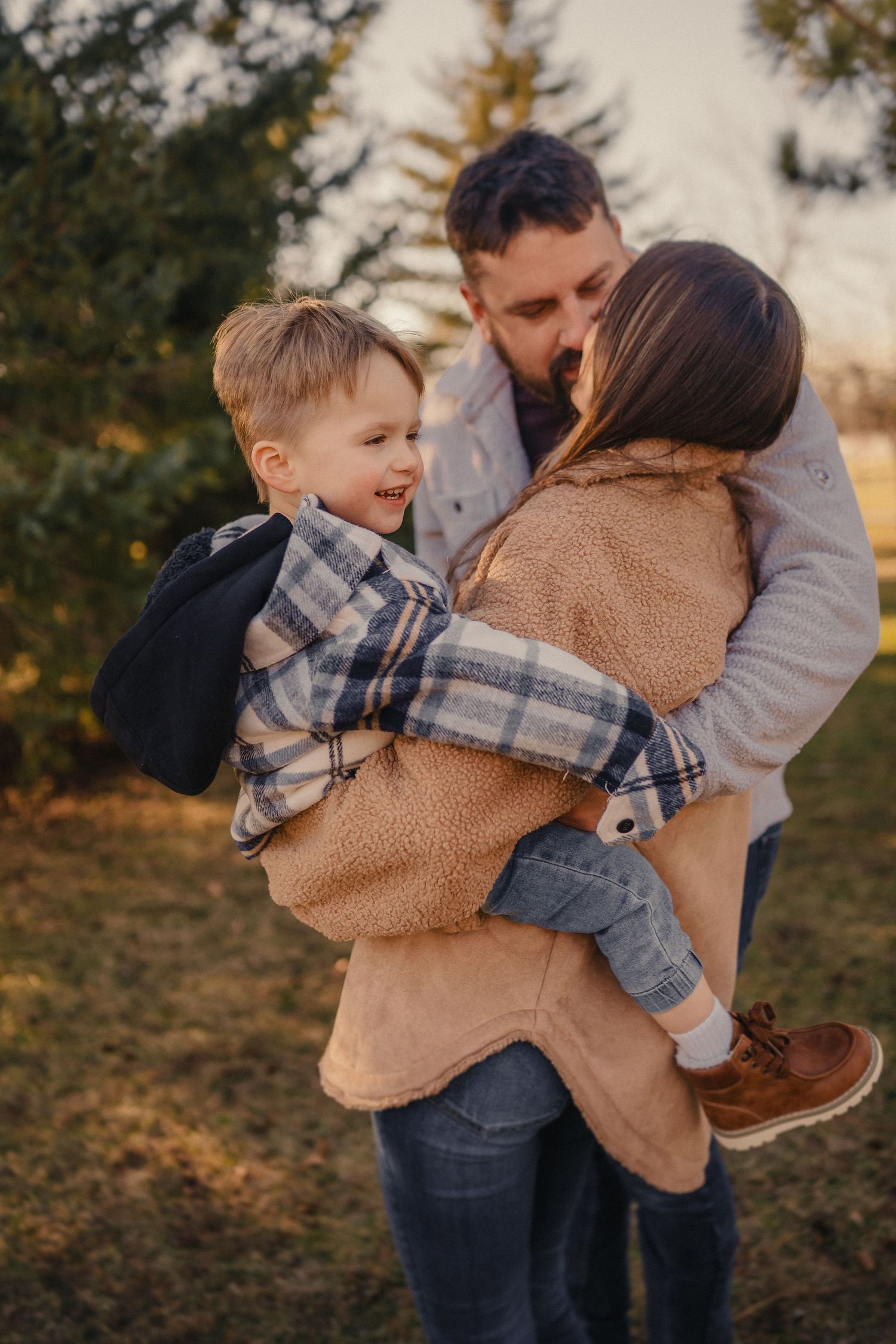 Family shares intimate moment outdoors at sunset with warm fall attire and cozy embraces in nature.