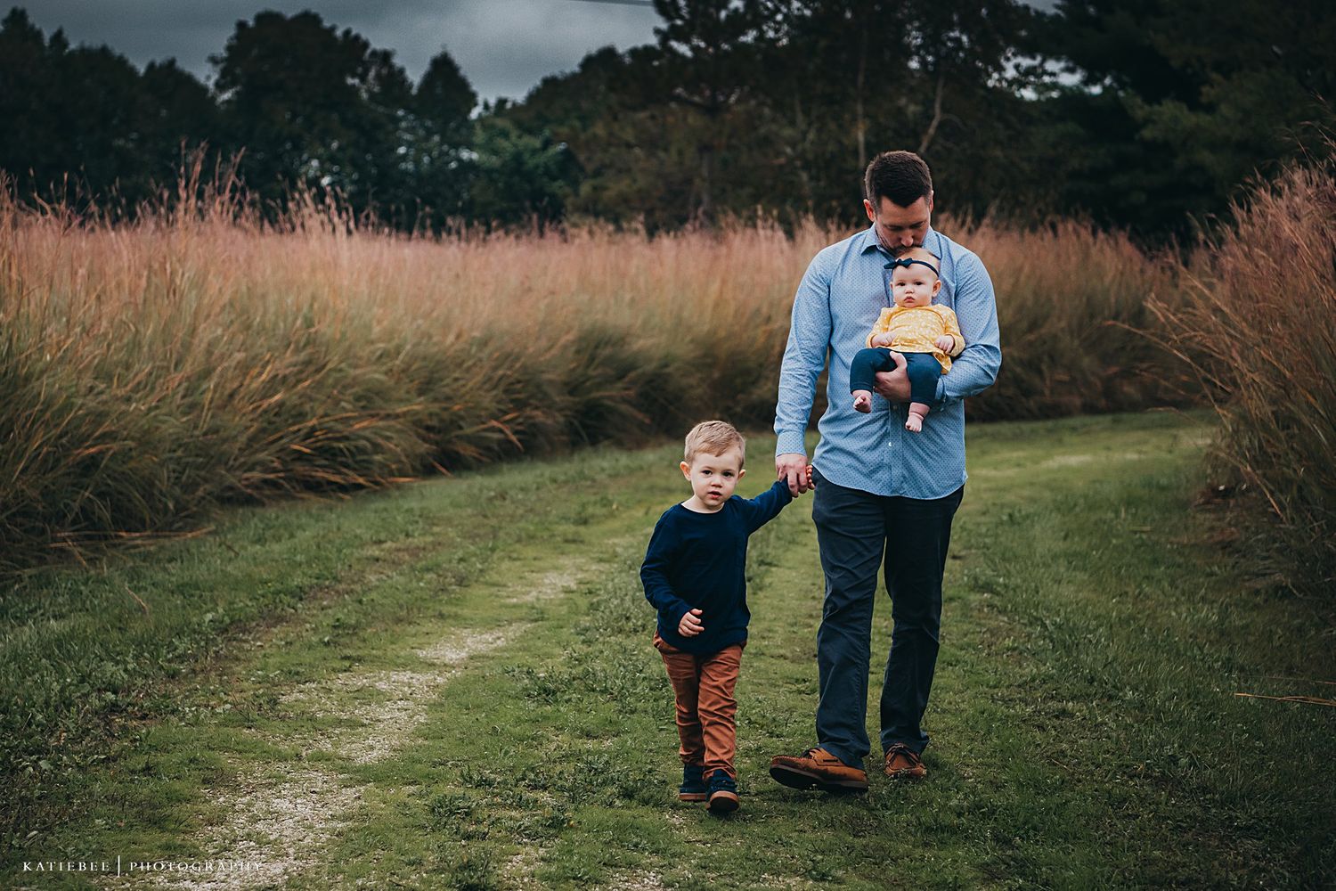 A casual family stroll along a path bordered by ornamental grasses.