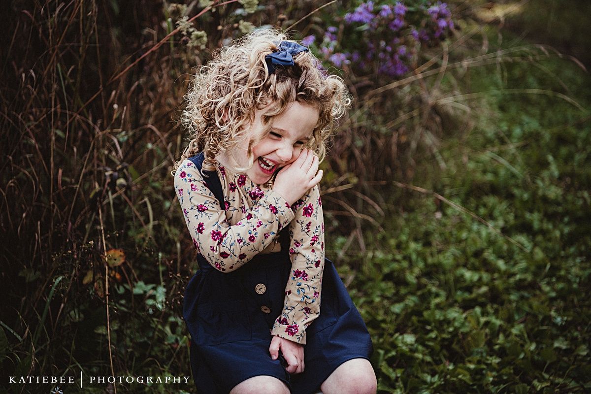 A playful portrait in a garden setting with purple flowers in the background.