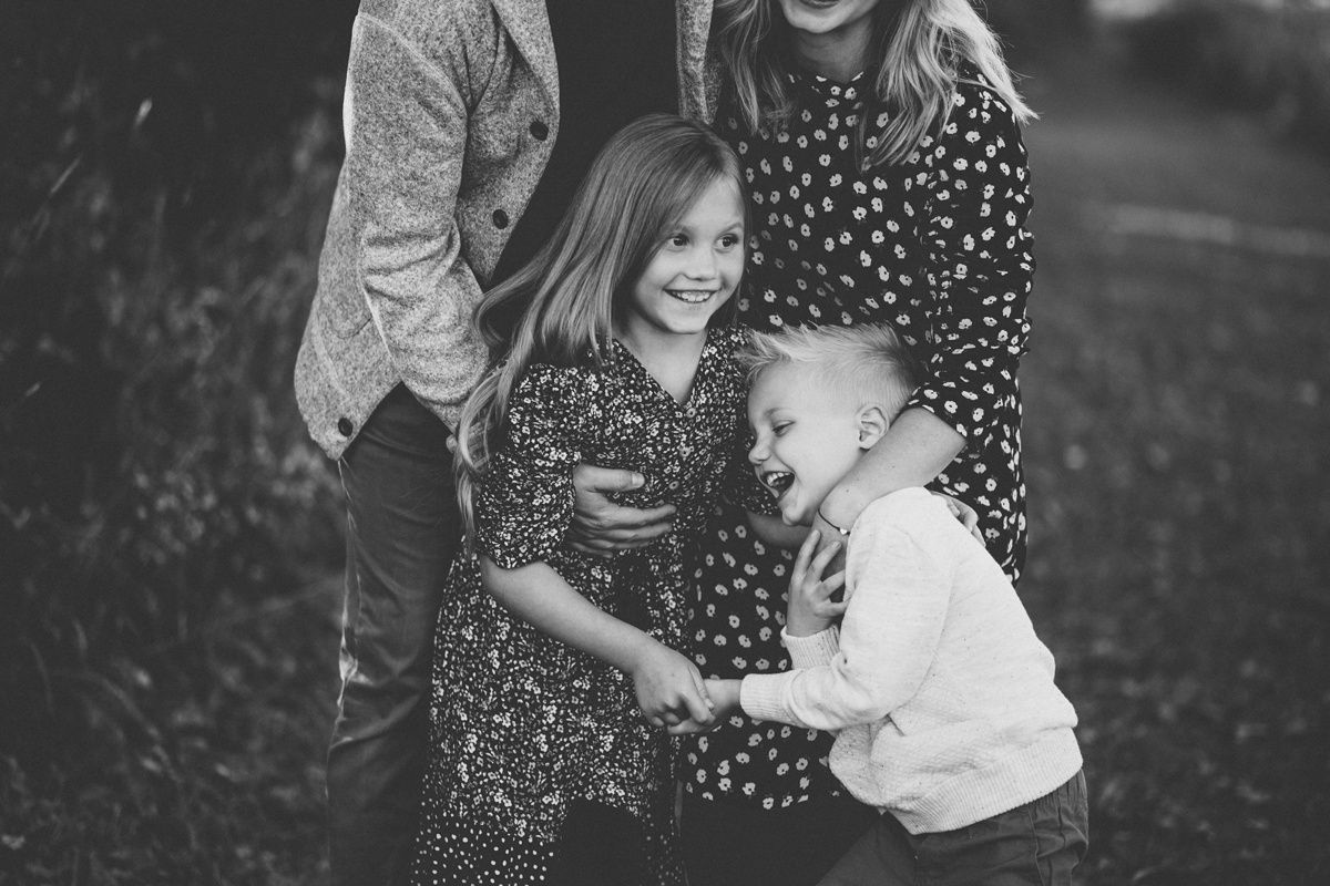Candid black and white family moment captured in nature with joyful expressions.