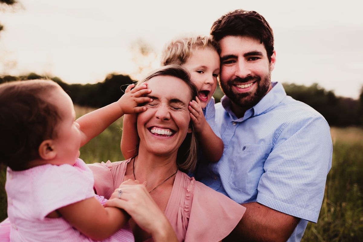 Candid family moment of shared laughter in an outdoor field setting.