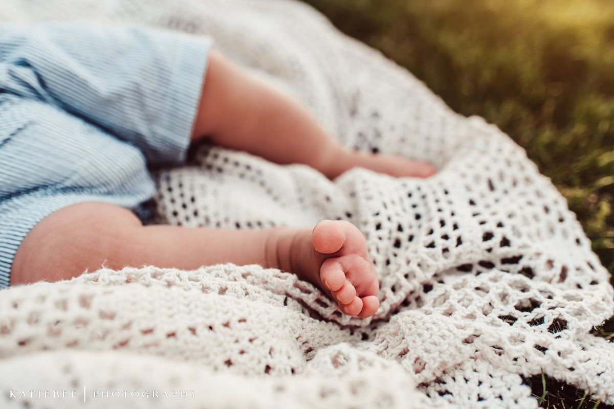 Close-up of baby's feet resting on white lace blanket in sunlight.