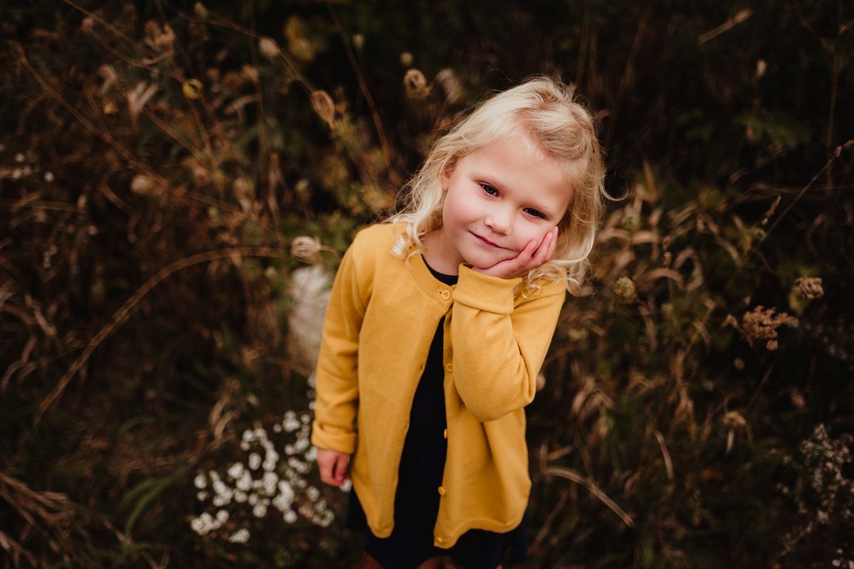 Cheerful moment captured in a mustard yellow jacket against fall foliage.