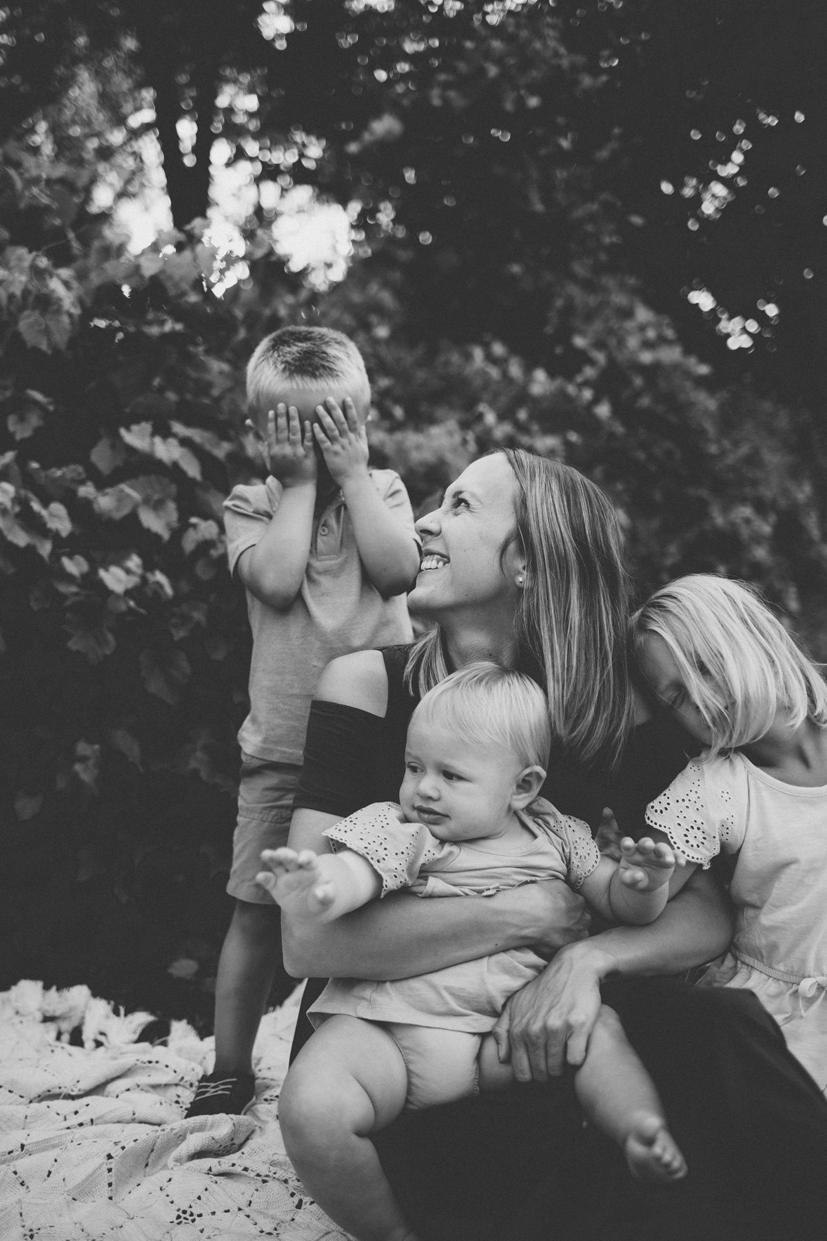 Black and white candid portrait of a playful family moment outdoors.
