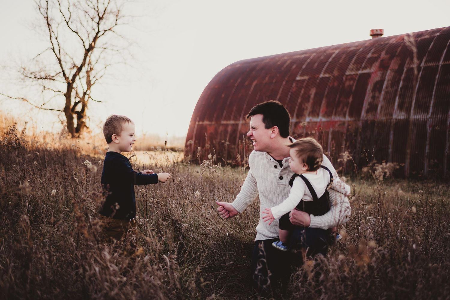 A playful family moment captured in front of a rustic barn during golden hour.