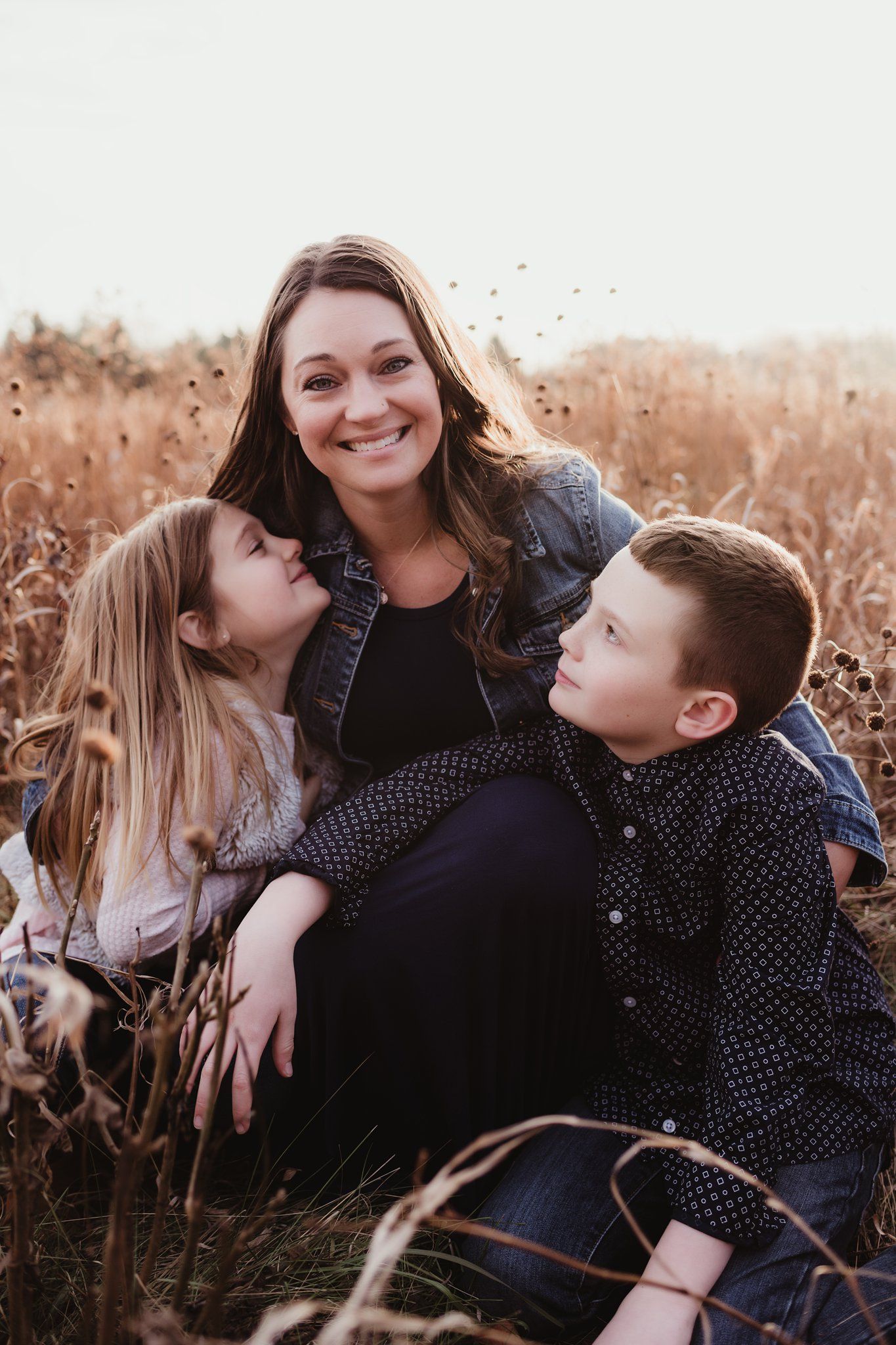 Family sharing intimate moment together in golden field during sunset.