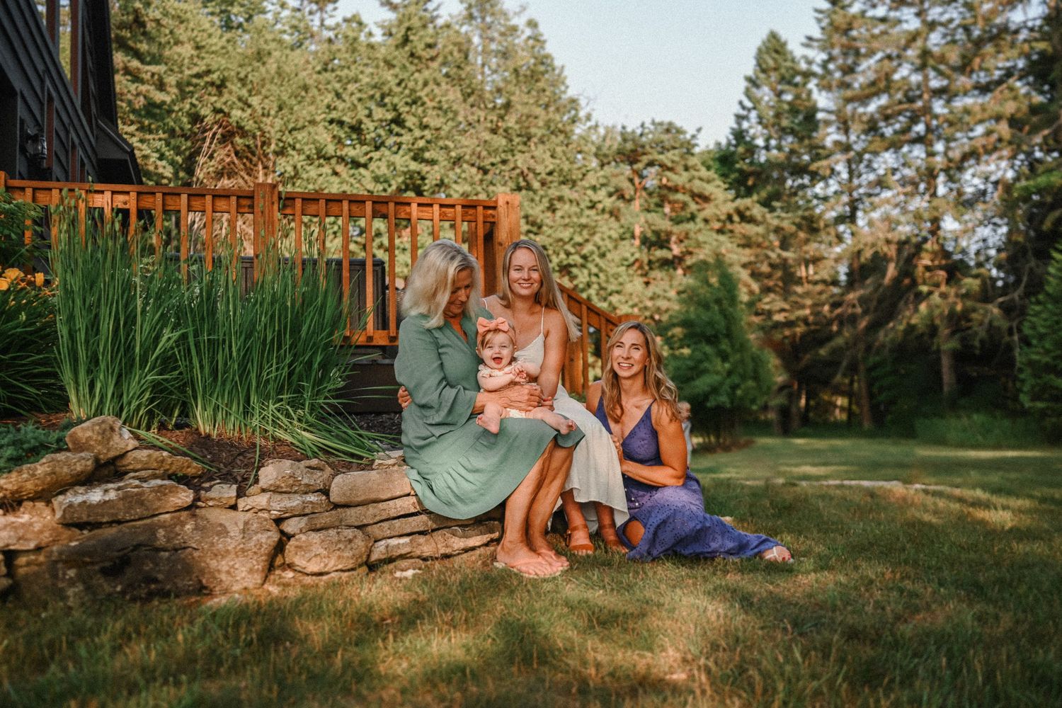 A relaxed family gathering in a backyard garden with stone wall and decorative grasses in summer.