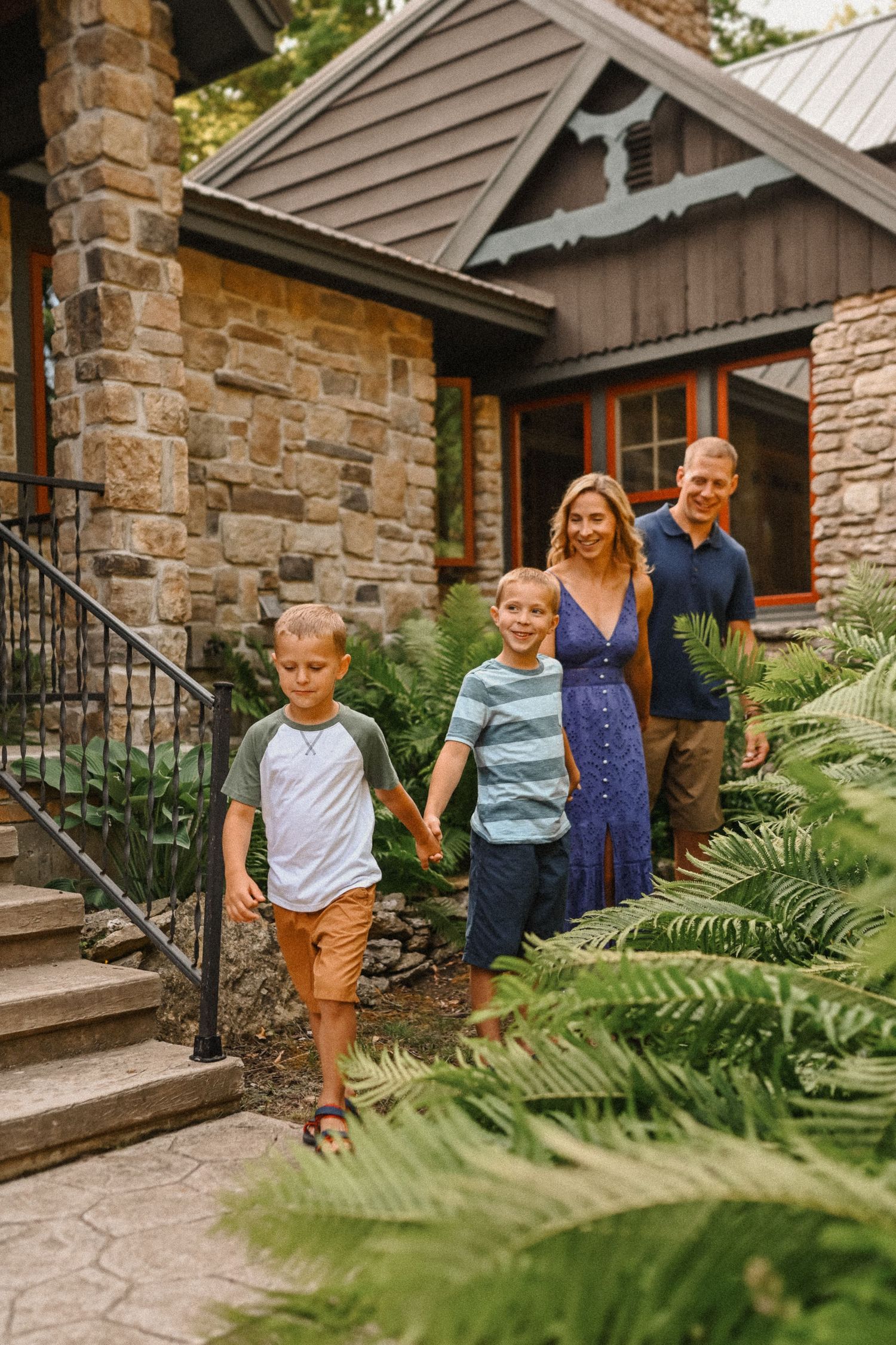 Family walking up stone steps leading to rustic cottage entrance.
