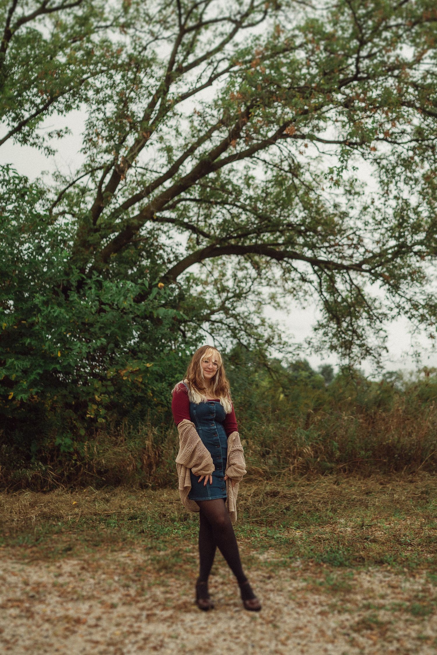 Autumn outdoor fashion portrait under large spreading tree branches.
