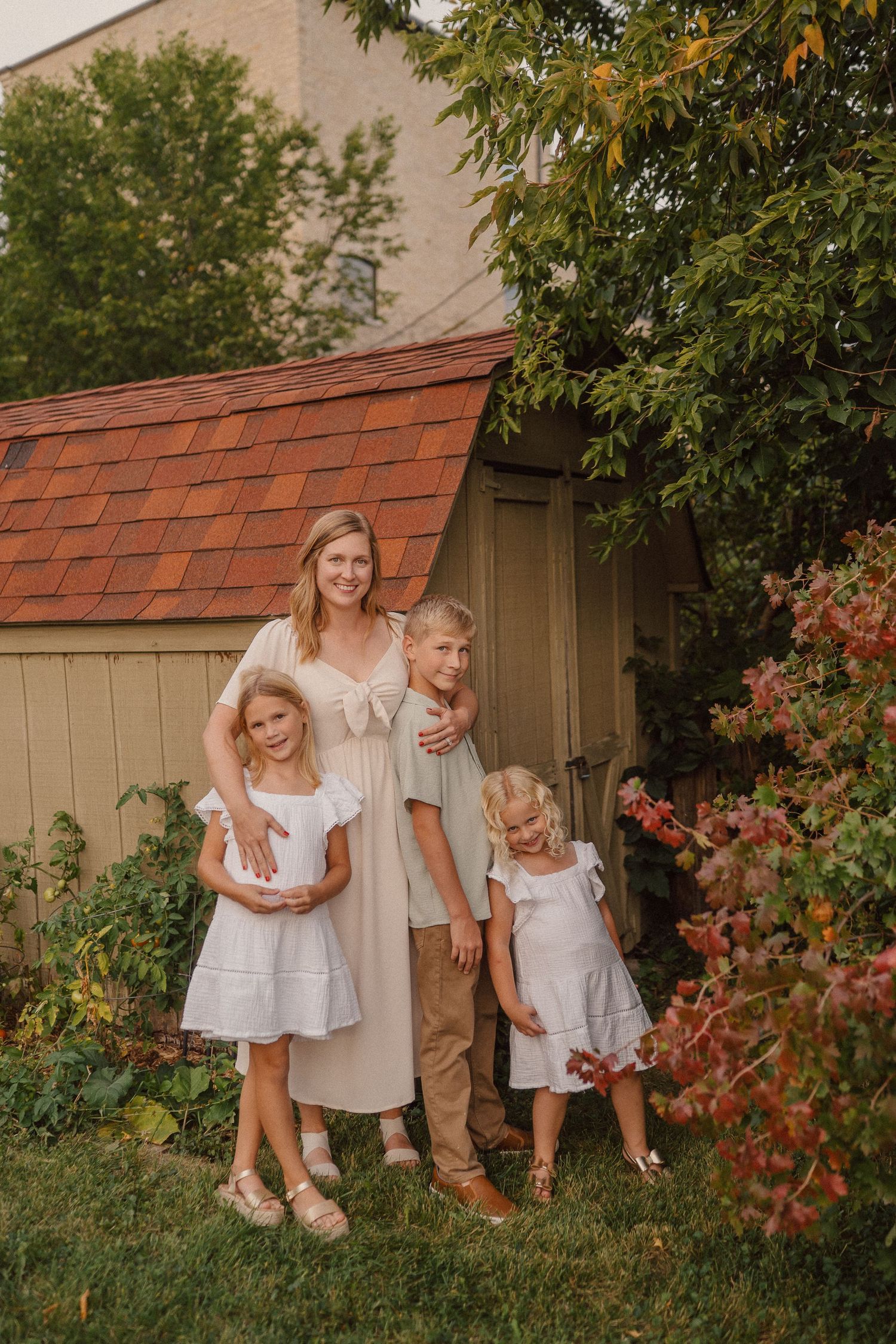 Family poses together by a garden shed with red roof tiles.