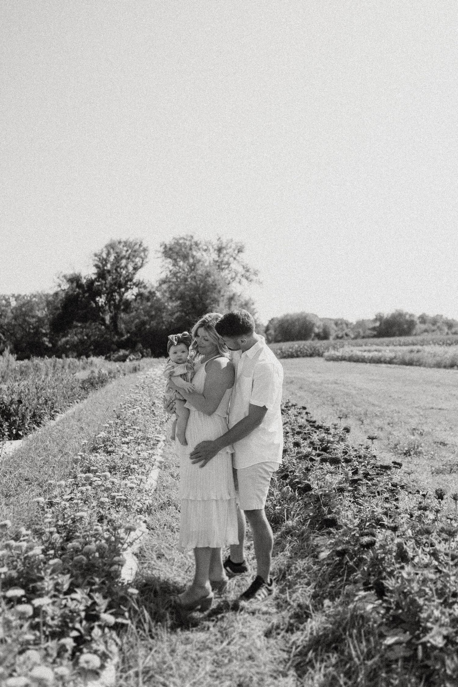 A romantic black and white moment shared between a couple standing in a rural field.