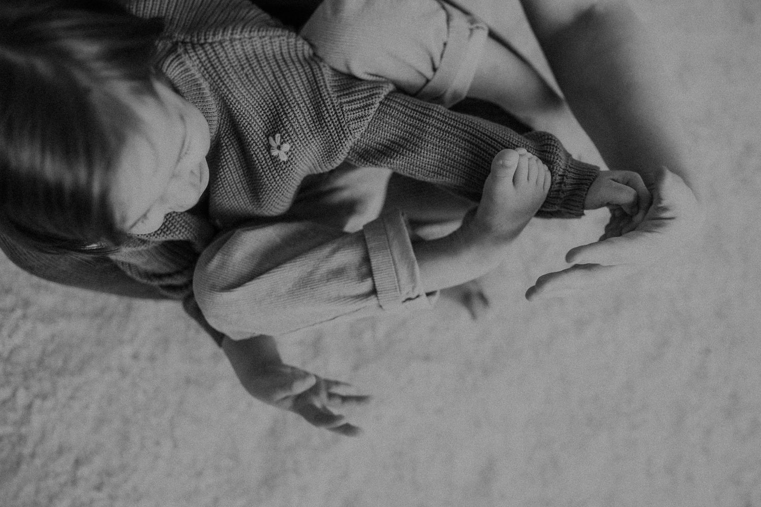 A person lying on a light colored carpet in monochrome.