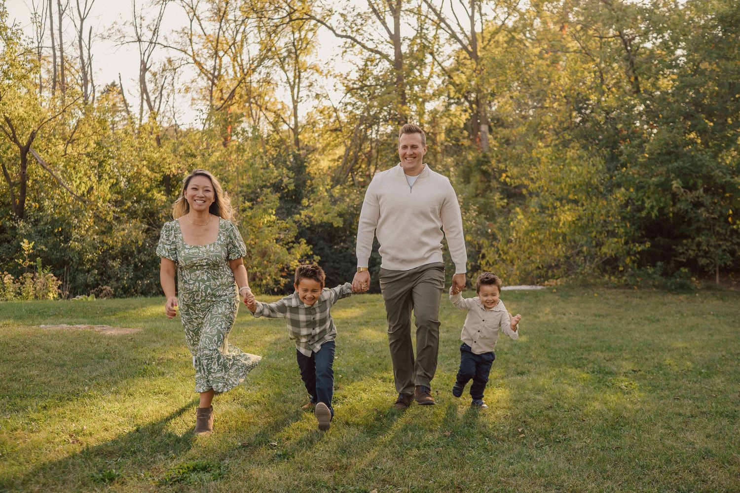 Family walking together through a sunlit autumn field during golden hour.