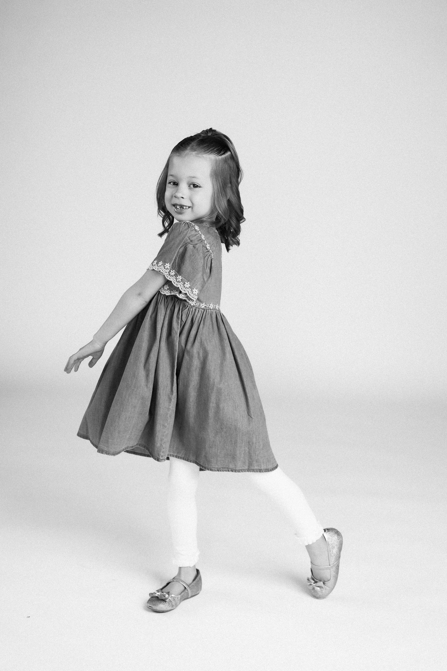 A series of black and white photos showing a young child in a dress twirling and dancing.