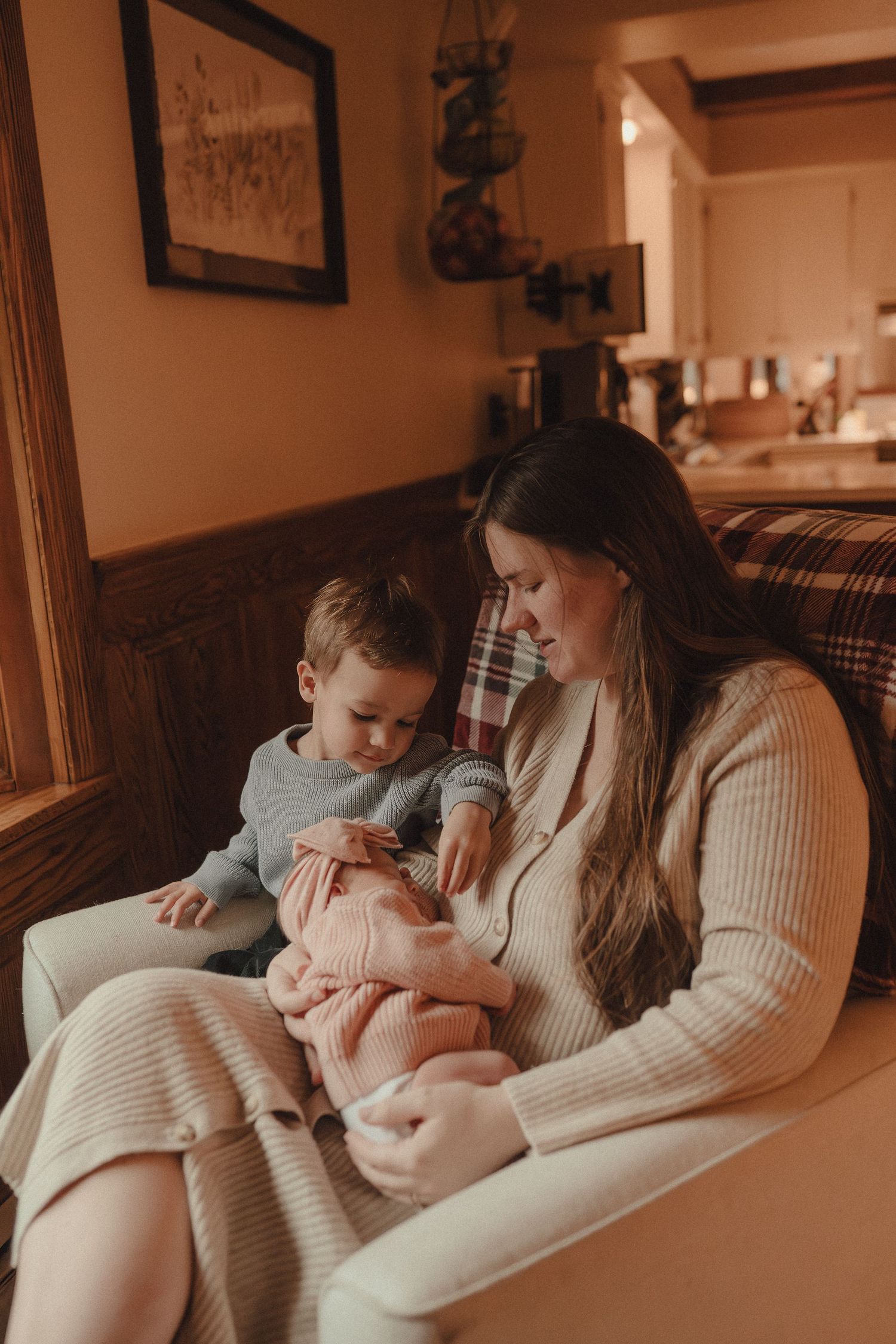 Tender moment captured in warm lighting as parent and newborn share intimate cuddles on cozy sofa.