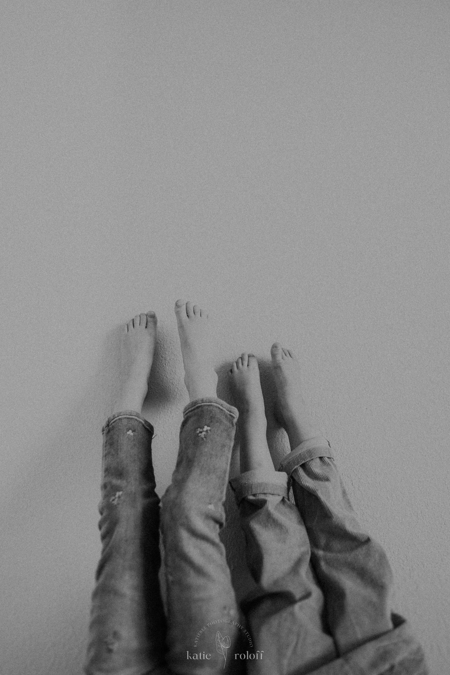 Black and white minimalist photo of bare feet against a light background.