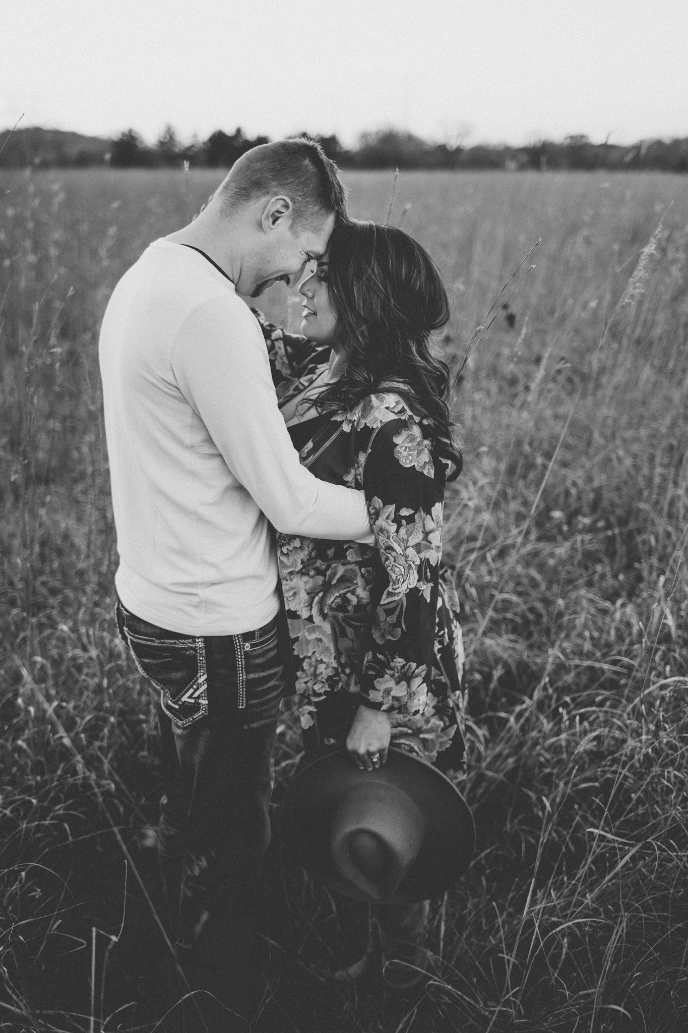 Monochrome portrait of couple in intimate embrace among tall grass.