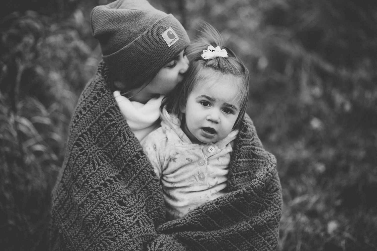 A tender moment captured in black and white as a child is wrapped in a cozy blanket.