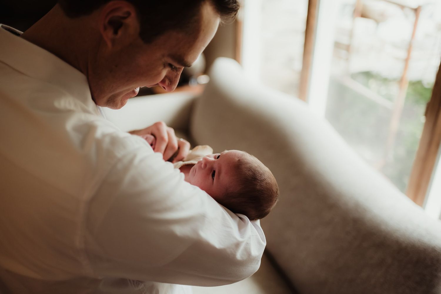 Tender moment captured between parent and infant in sunlit room.