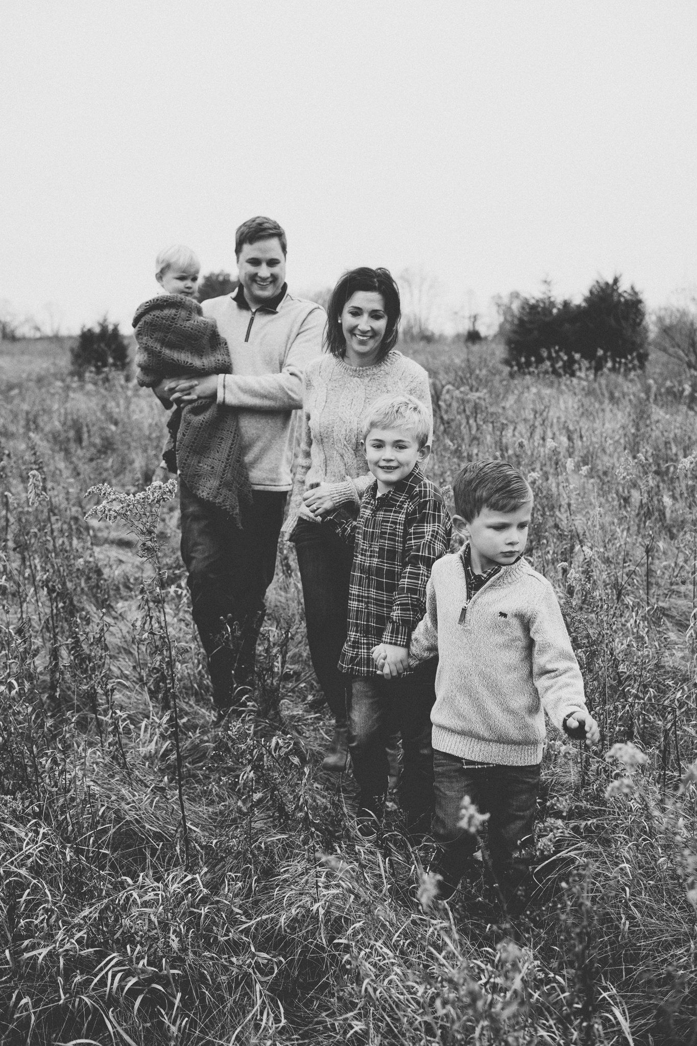 A family poses together in a rustic field setting shown in black and white.