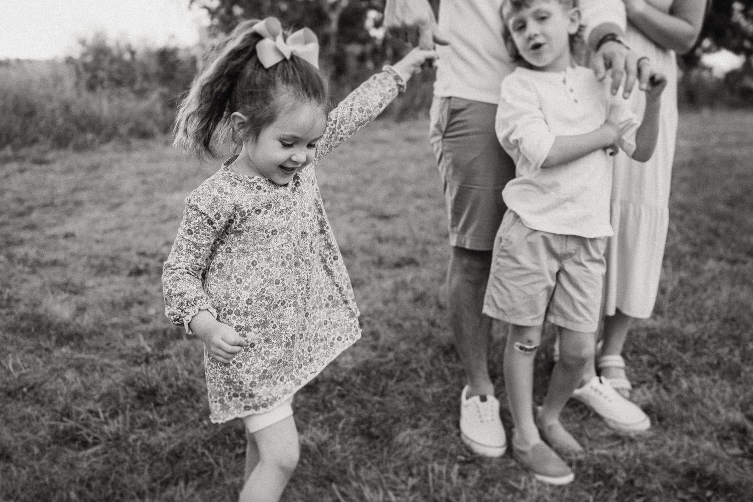 Black and white photo of children playing and jumping outdoors.