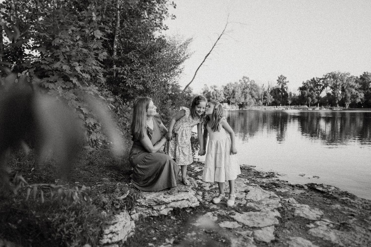 Black and white portrait of people sitting along a peaceful lakeside.