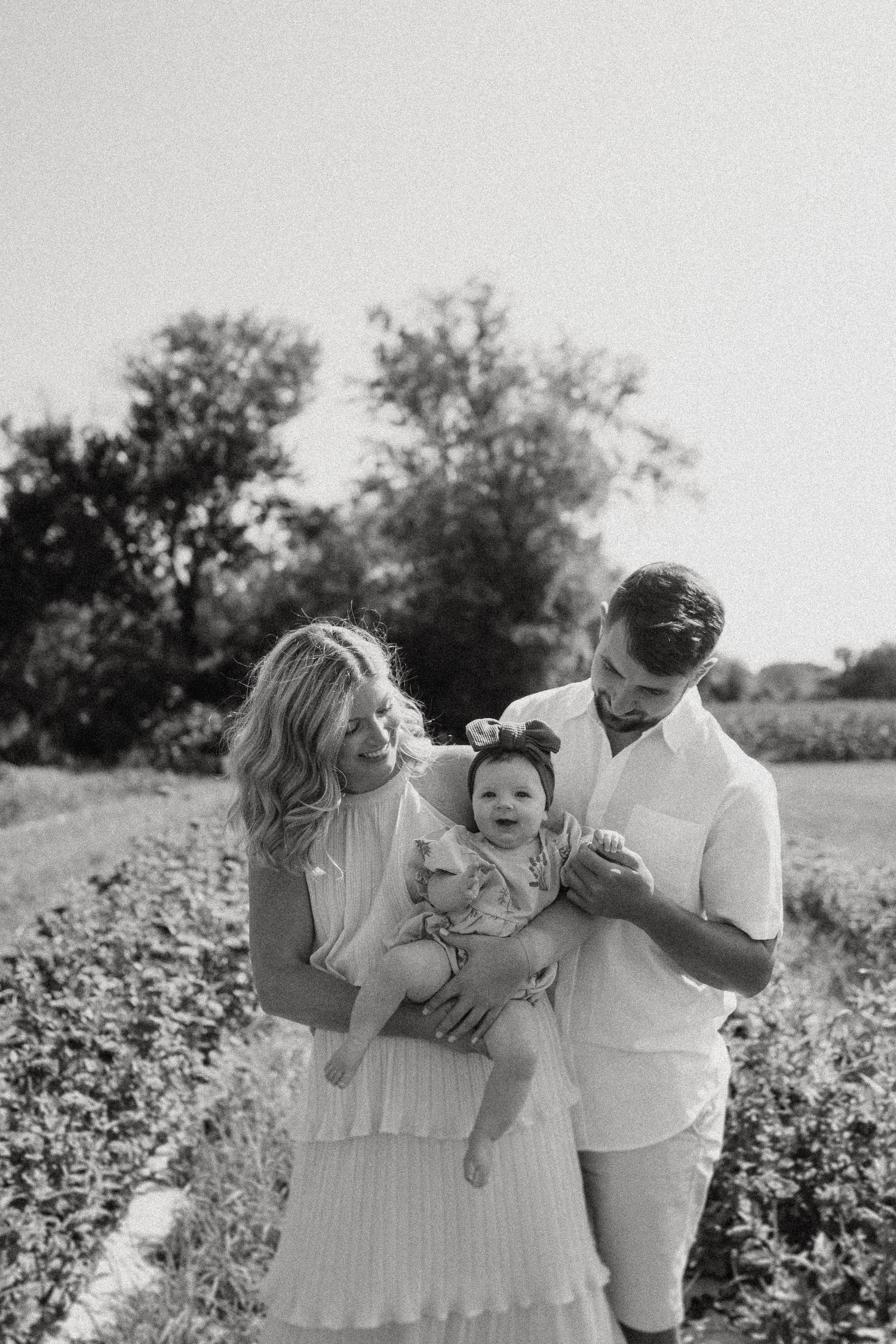 A black and white family portrait in a summer field.