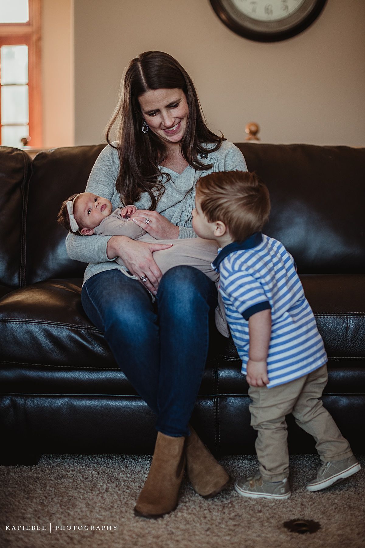 Cozy living room scene with family bonding on leather couch under wall clock.