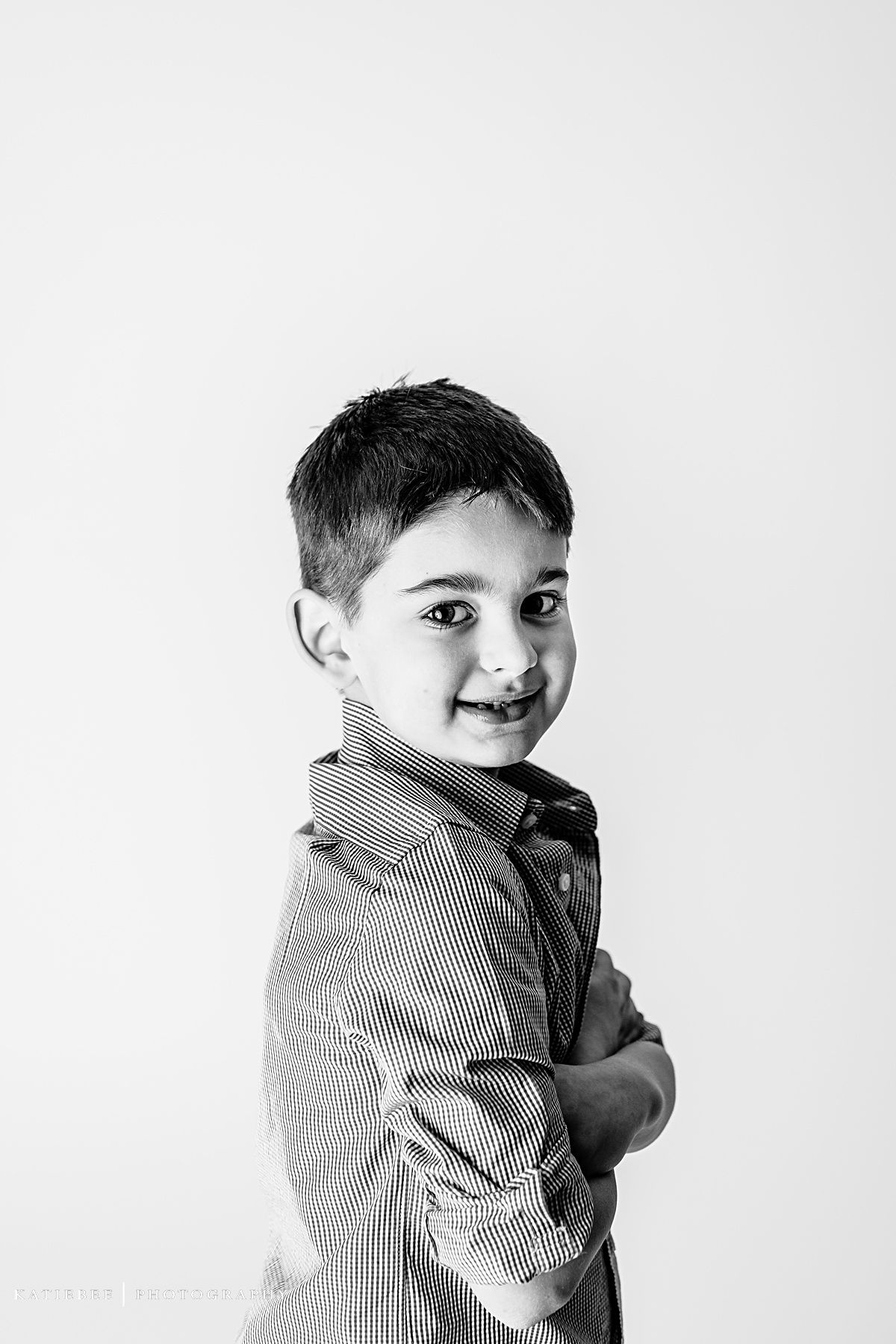 Side-angle portrait of child in striped shirt with gentle smile against white background.