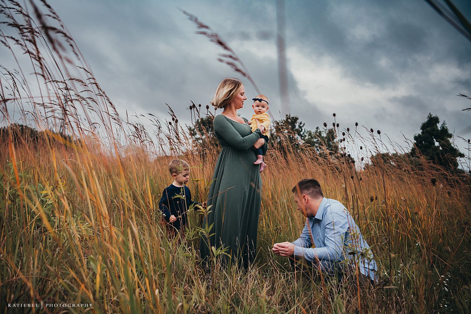 Family spending time together in a golden field under moody sky.