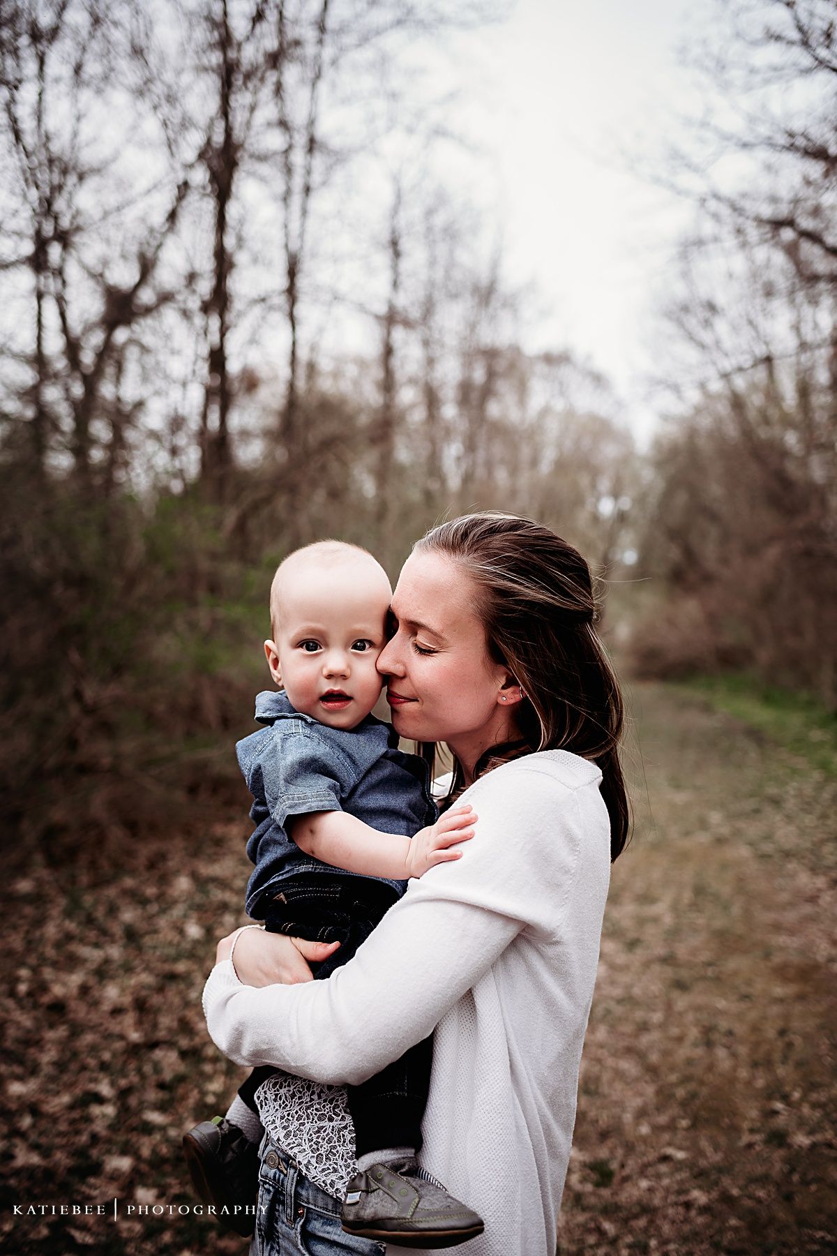 Intimate outdoor portrait showing tender moment on wooded path.