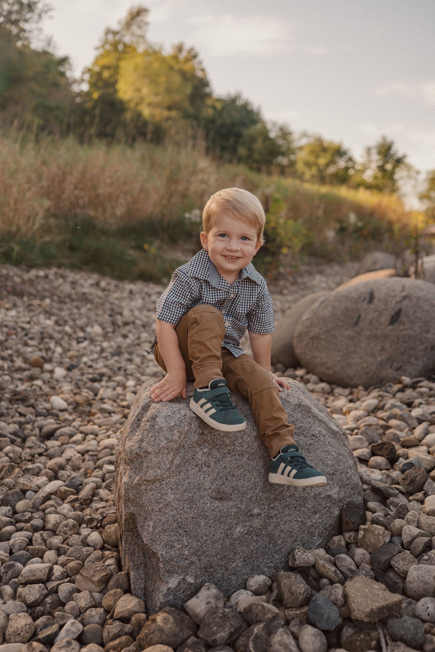 Child playing on large rocks by the shoreline during an overcast day.