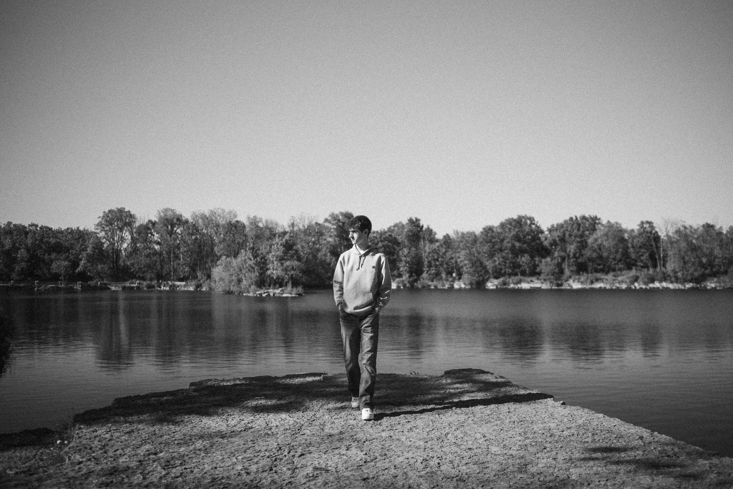 A series of black and white landscape photos showing a couple walking along a tranquil lakeside path.