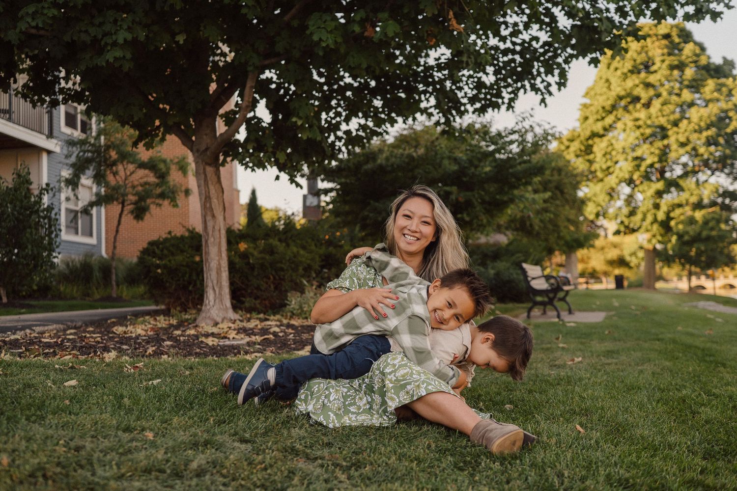 Family relaxing together on a grassy hillside during a warm sunset.