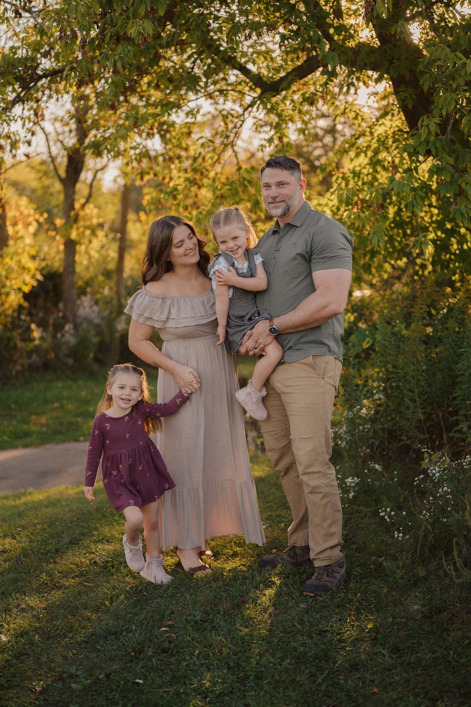 Family enjoying a warm autumn evening together outdoors in a natural setting with golden sunlight filtering through trees.