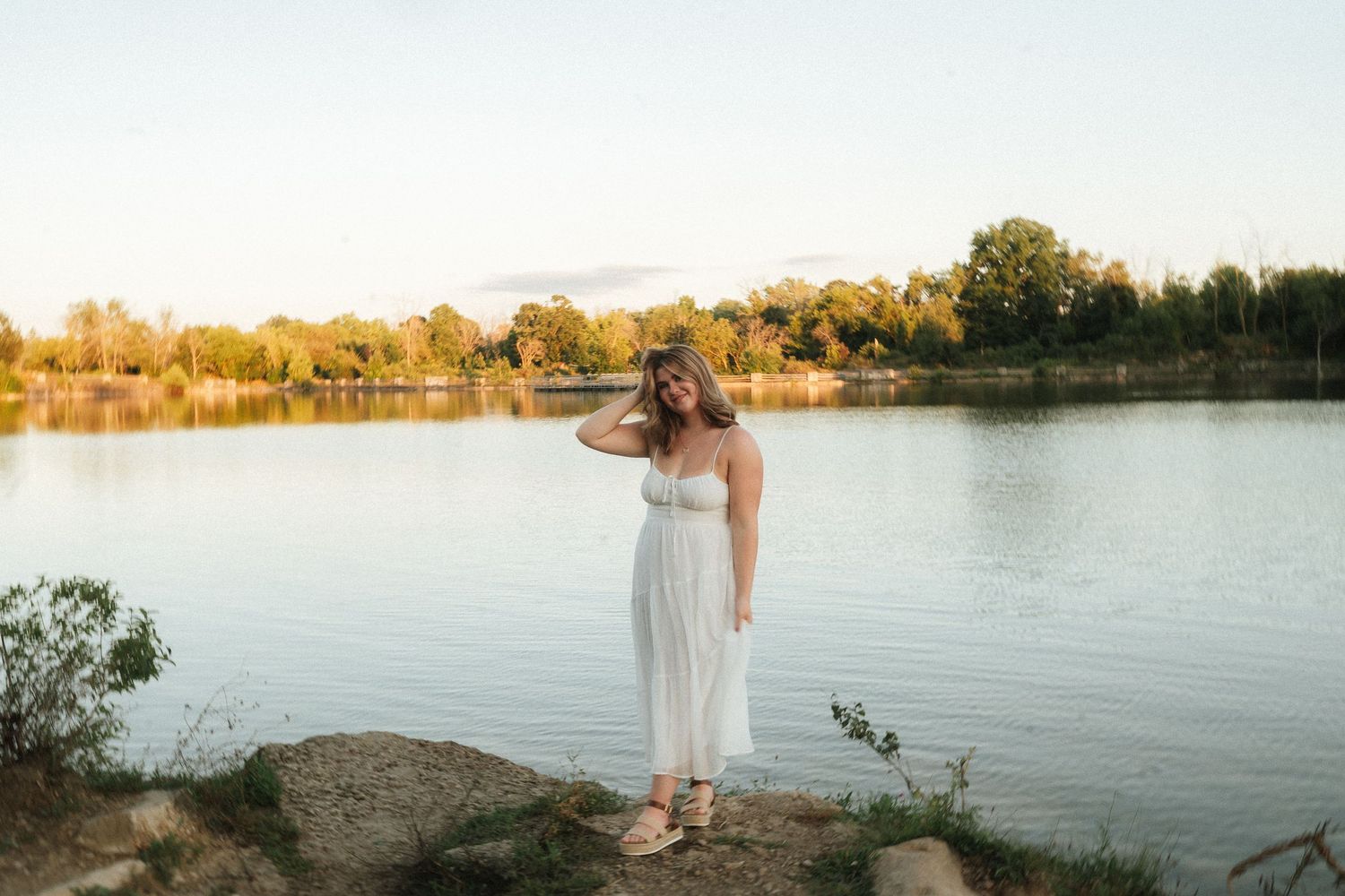 Woman in a dress dancing in a rustic field at dusk.