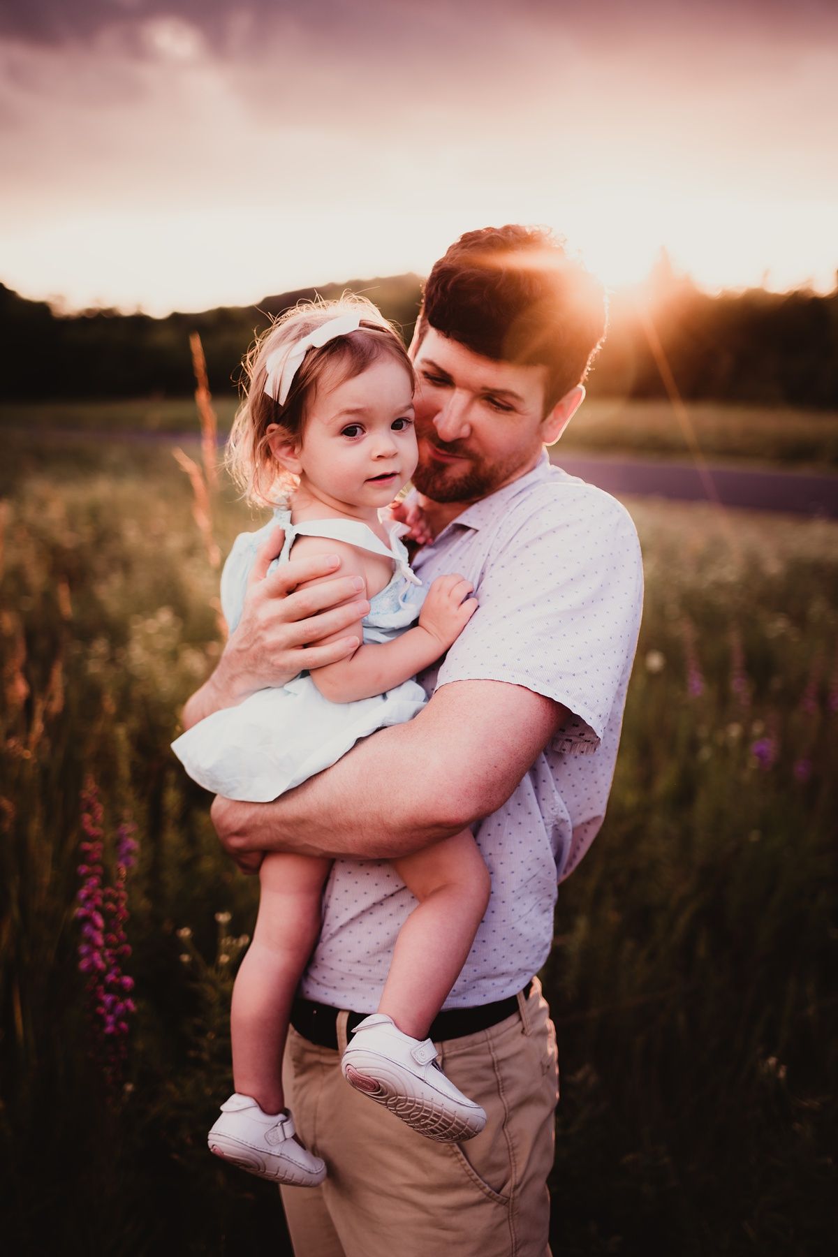 Intimate moment between parent and child surrounded by wild summer flowers at dusk.
