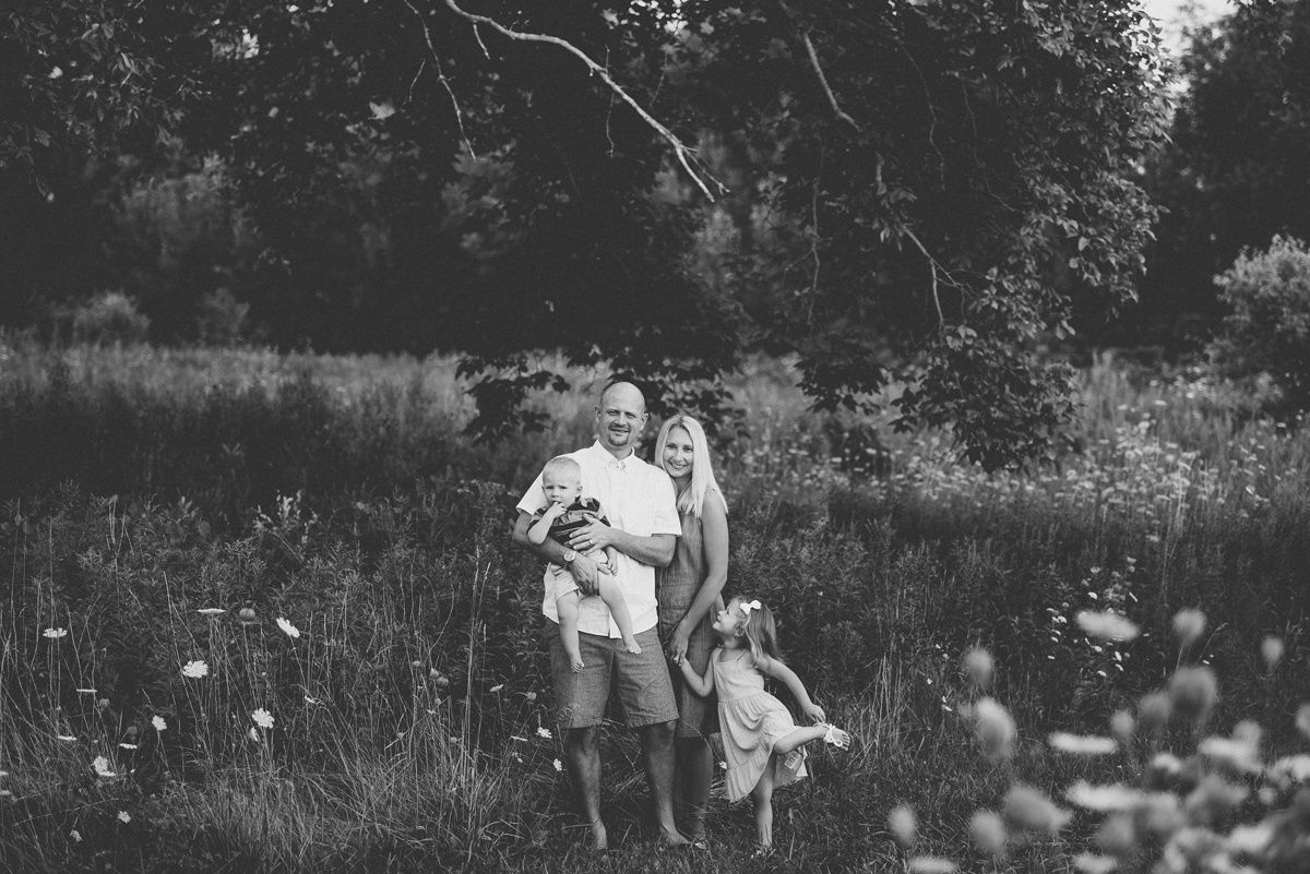 Black and white photograph of a family standing together in a wildflower meadow.