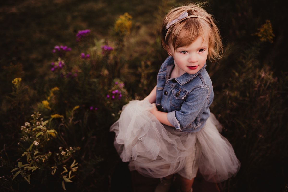 Portrait in a wildflower meadow showing whimsical fashion with denim and tulle.