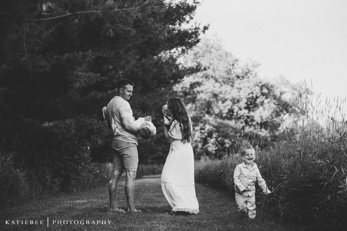 Black and white portrait of a family walking together on a nature path.