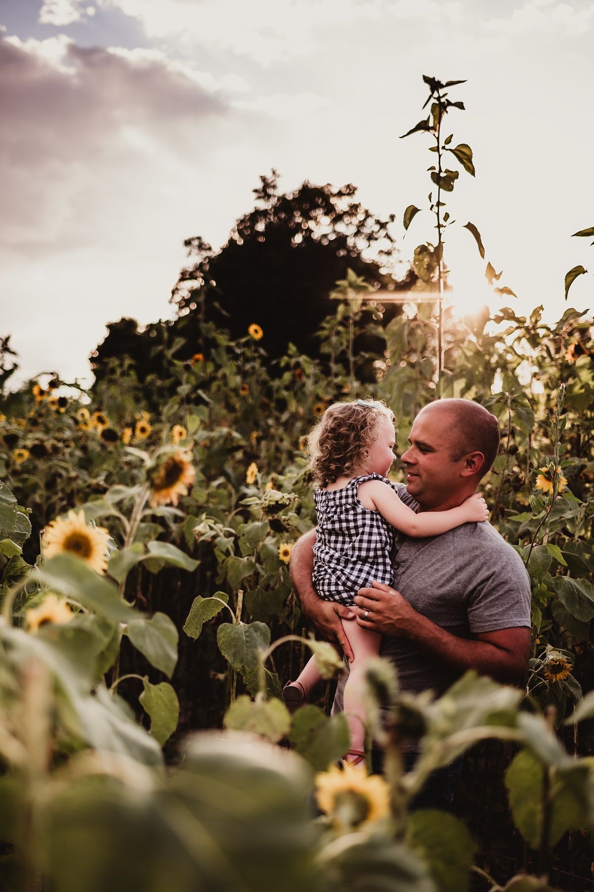Tender moment among towering sunflowers during golden hour sunset.