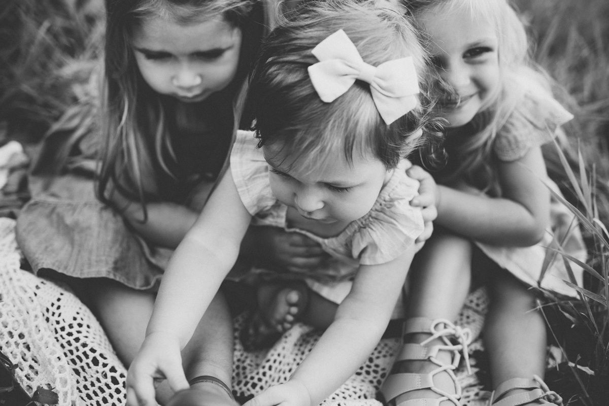 Black and white close-up of children sharing a playful moment together.