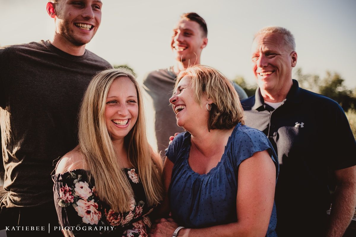Group of people laughing together during an outdoor family photo session.