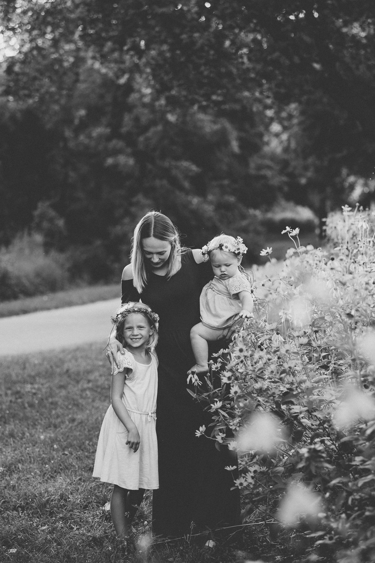 Black and white family portrait taken outdoors near blooming wildflowers.