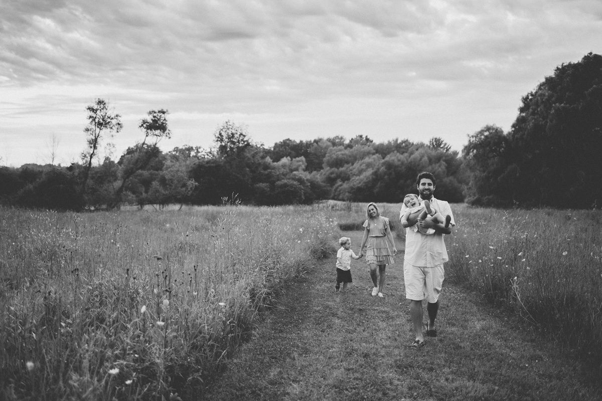 A black and white image of people walking along a path through a wildflower meadow.