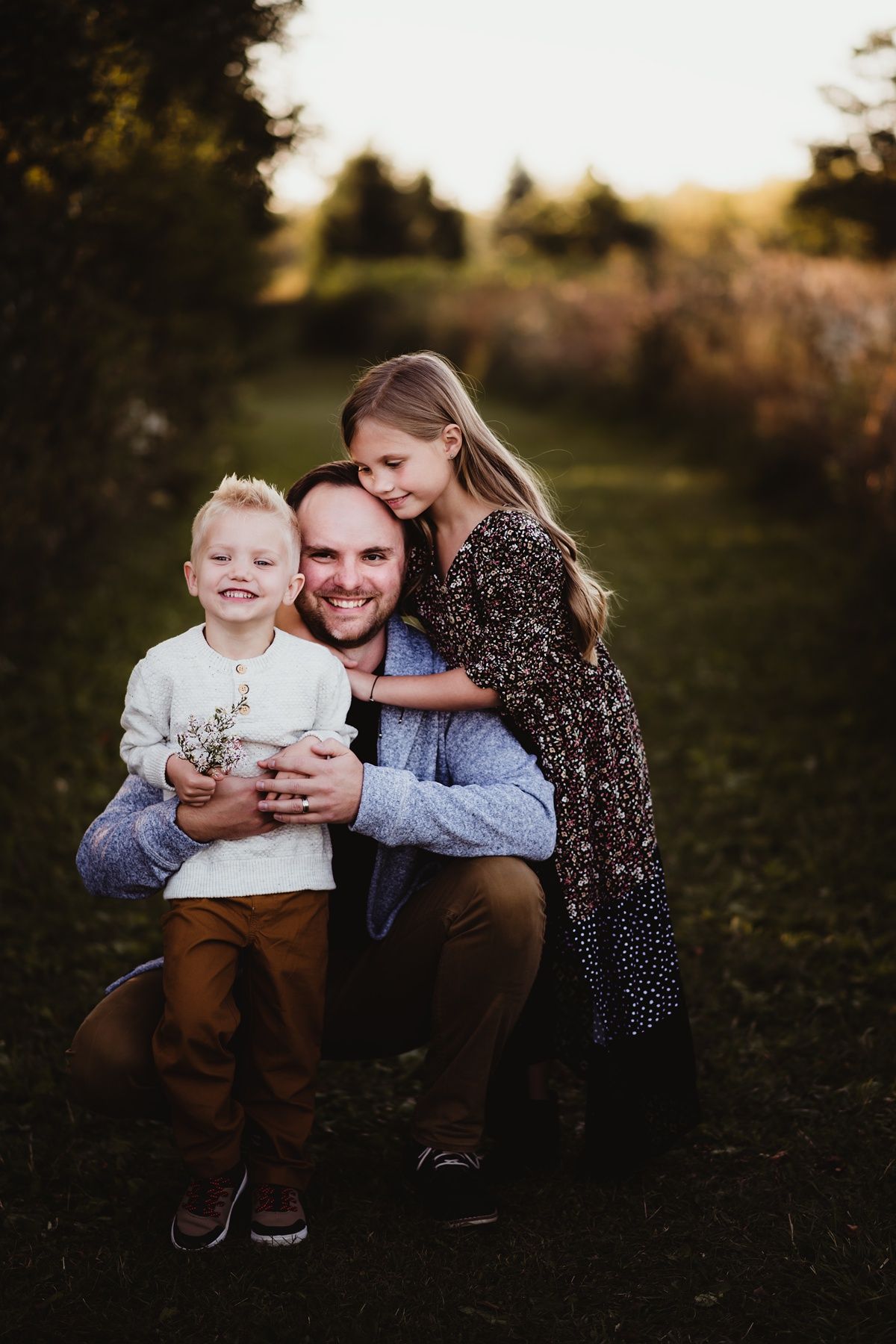 Sweet family portrait outdoors with beautiful sunset lighting in the background.