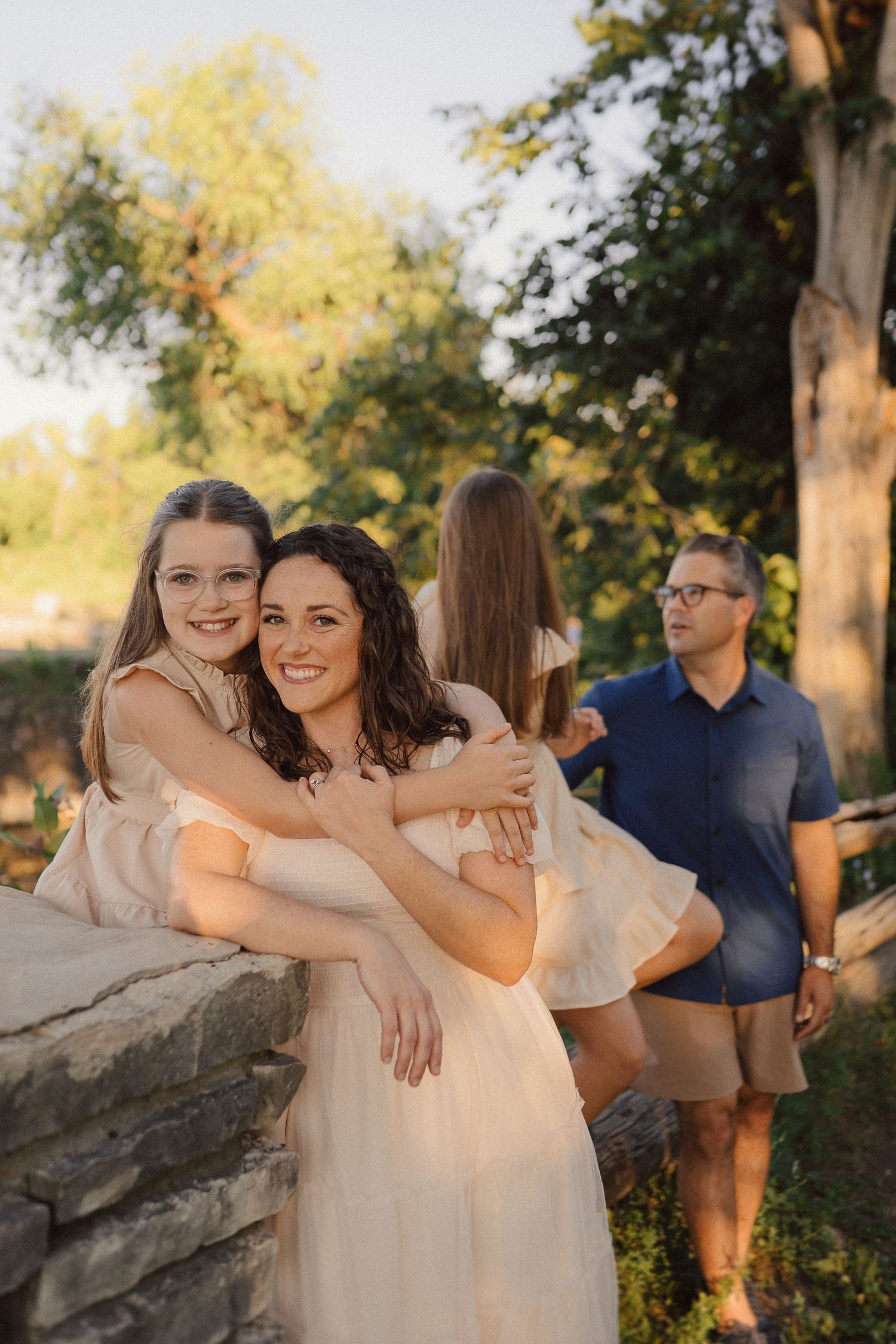 People sharing intimate moments while sitting on large rocks during sunset in a park.