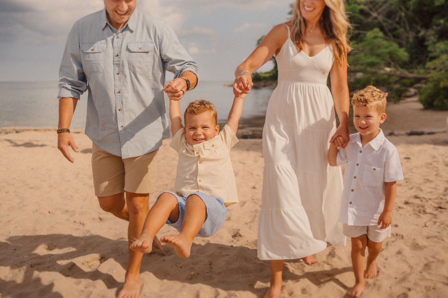 A joyful walk along the beach at sunset with coordinated white and neutral outfits.